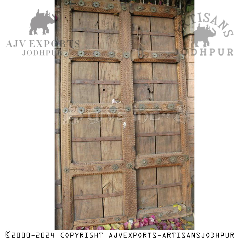 A traditional Indian door with detailed wood carvings and elegant brass handles.