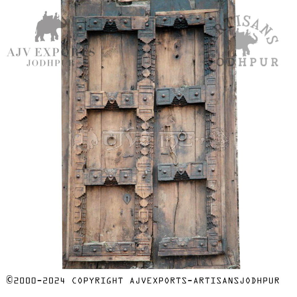 An antique Indian door with metal reinforcements and a faded wooden finish.