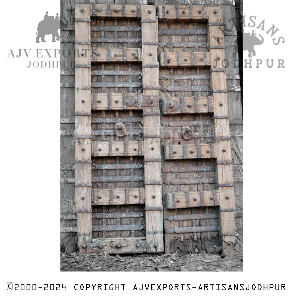 A heavy-duty Indian fortress door fortified with iron bolts and made of aged wood.