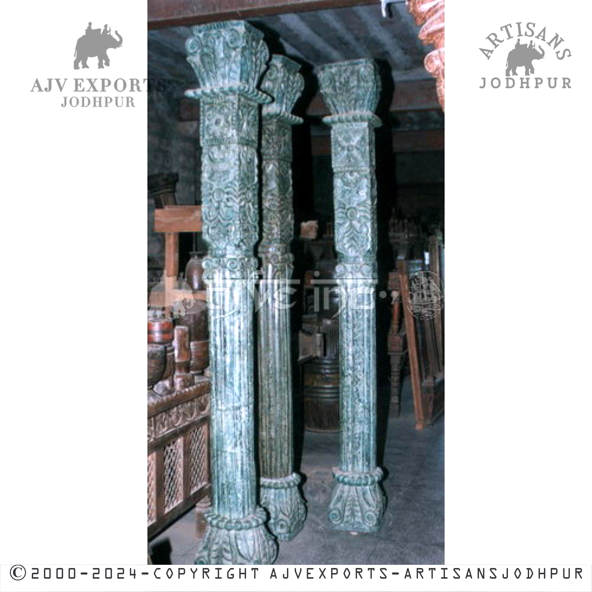 Several robust, teal-colored wooden columns with ornate carvings, presented in an antique furniture setting.