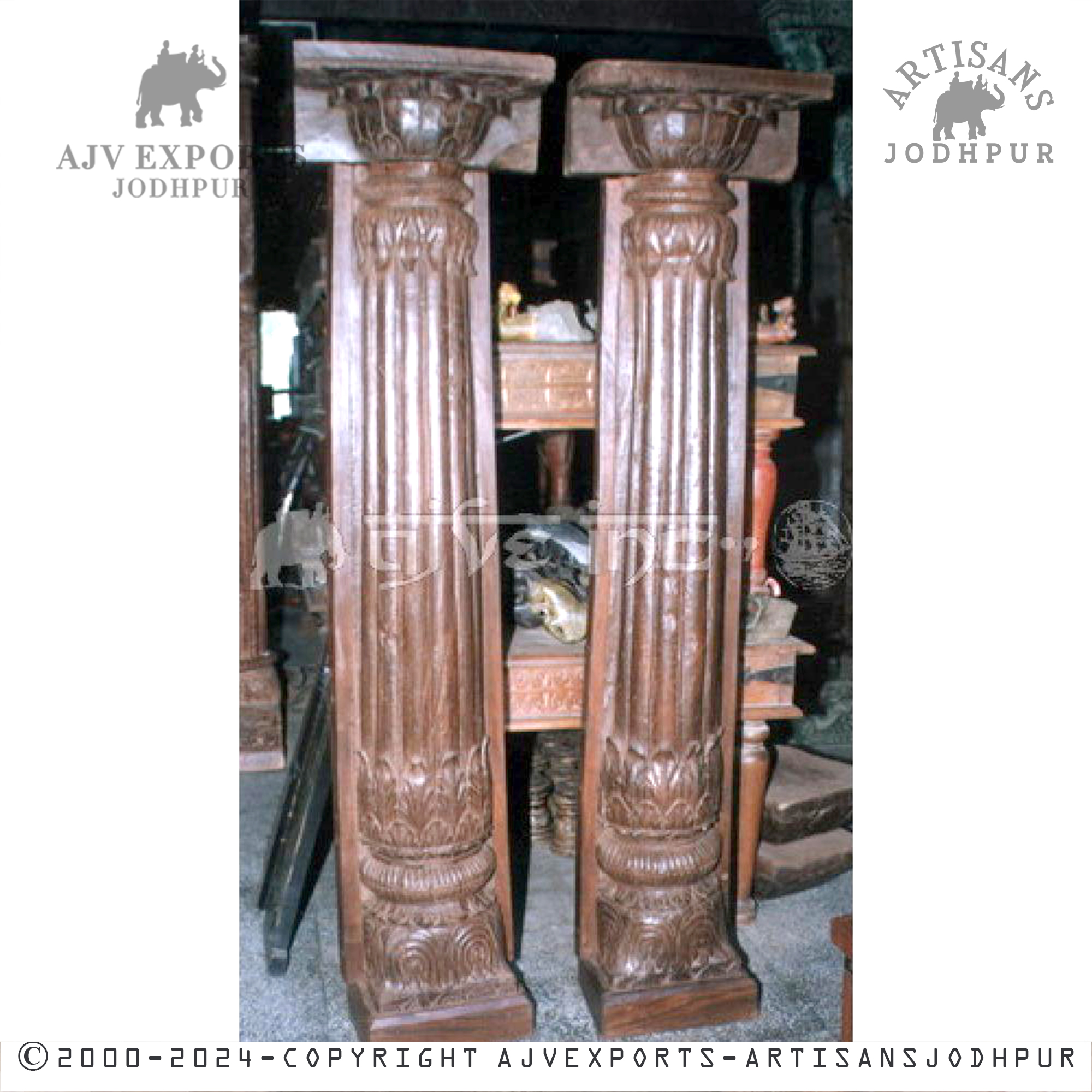 Two tall wooden columns with ornate capitals and deep fluting, showcased in an interior decor setting.