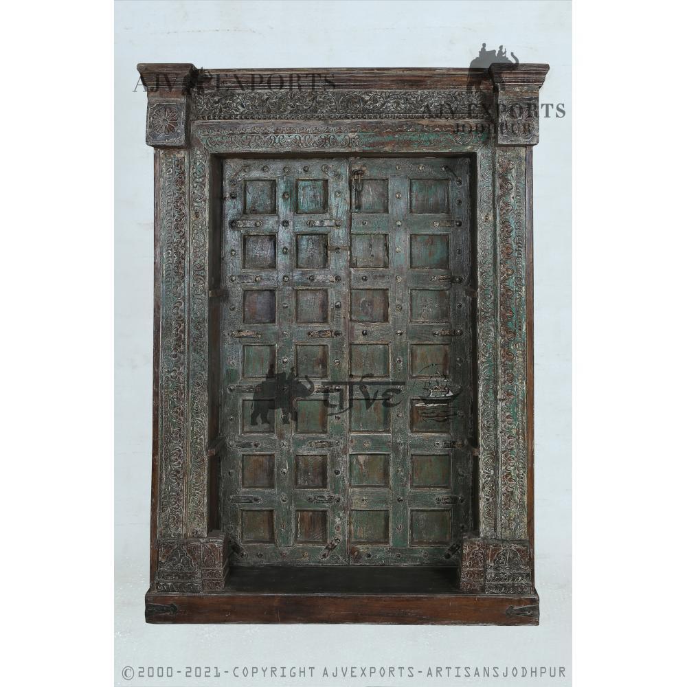 Antique wooden door in distressed green with a carved frame