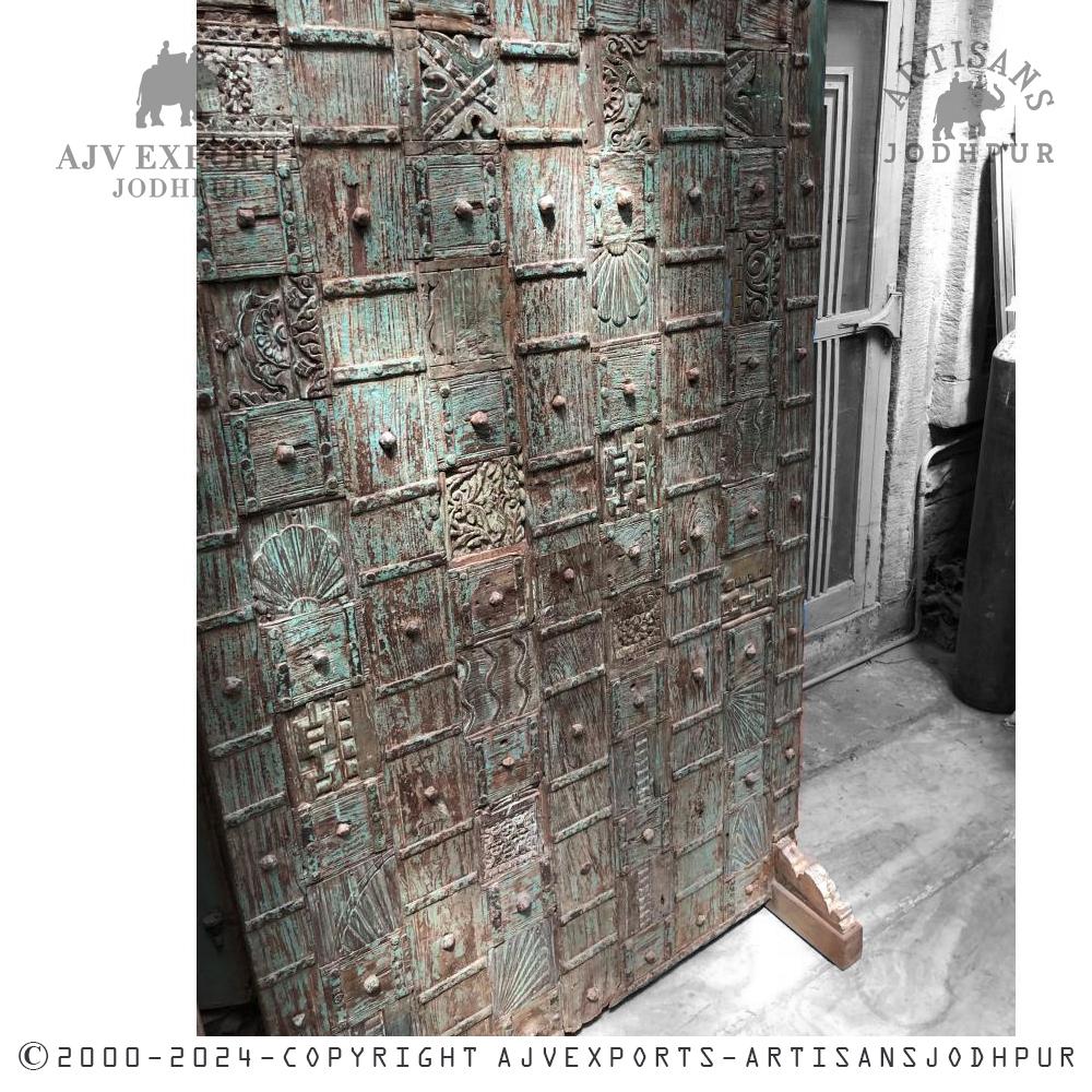 Wooden door with intricate panel carvings and distressed patina