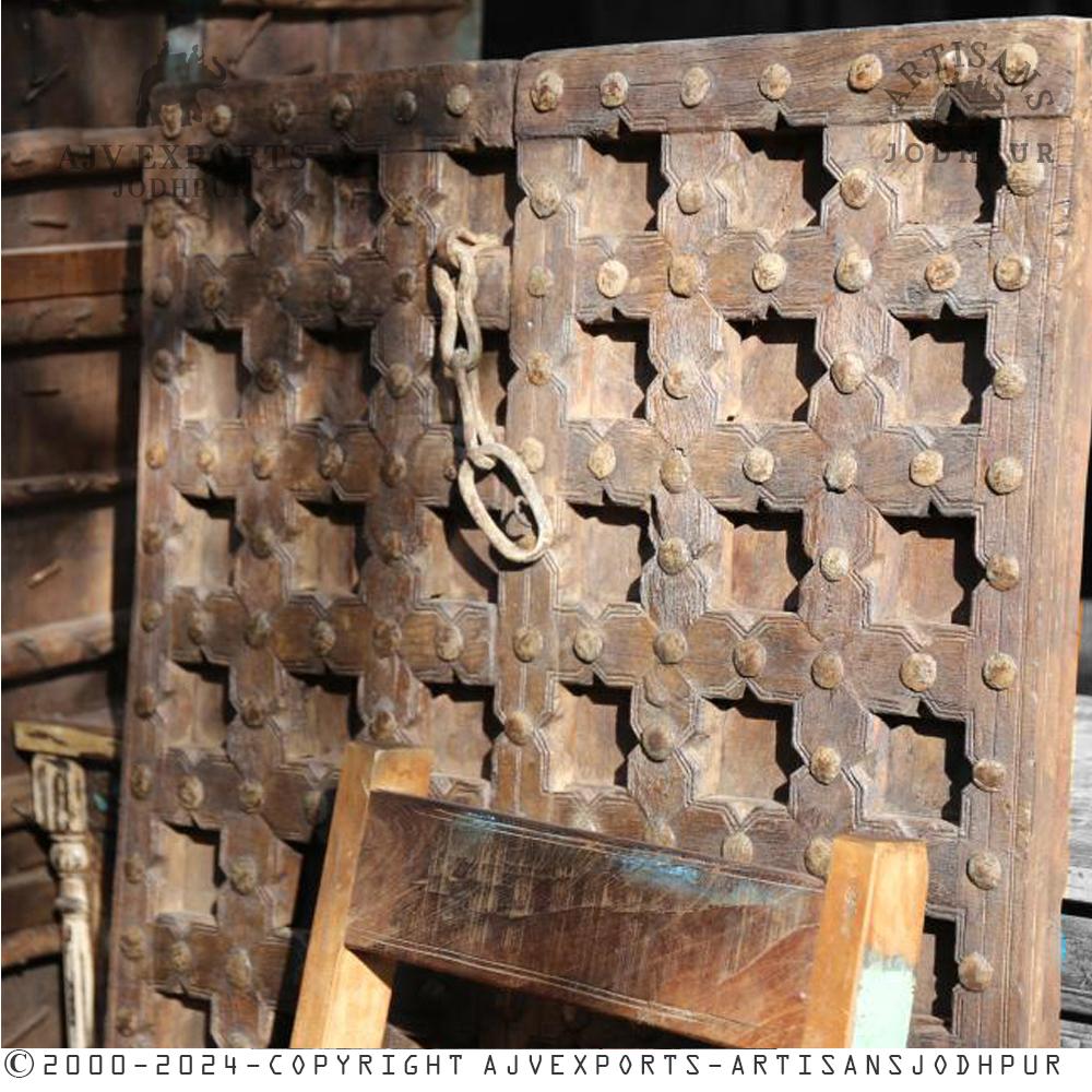 A rustic wooden door featuring metal studs, capturing the essence of ancient Indian architectural styles.