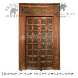 Wooden door with brass studs and geometric carvings