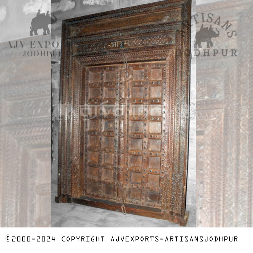 A sturdy antique wooden door with metal studs and embellishments, emphasizing a rustic charm from Jodhpur, India.