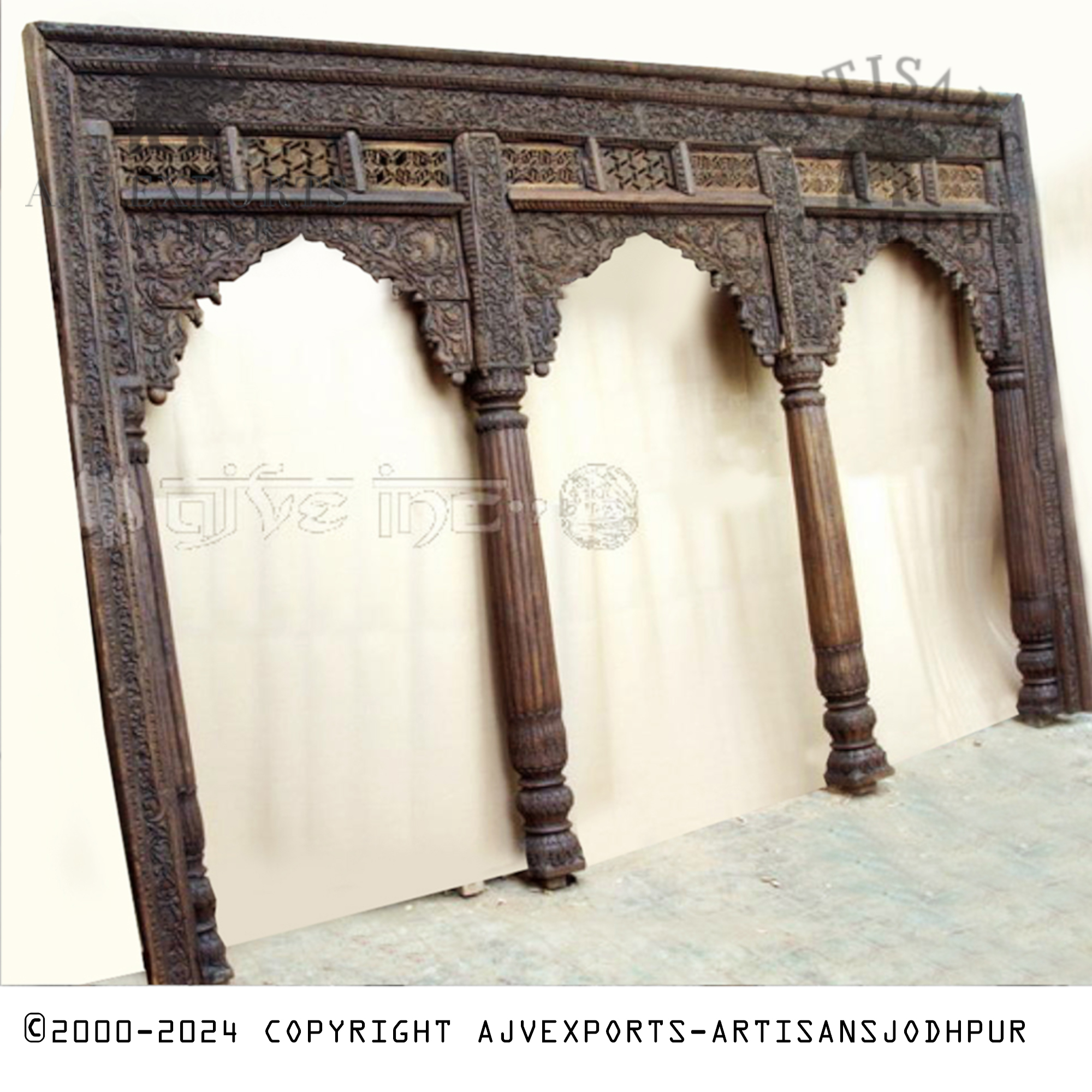 An ornate wooden archway from Jodhpur with detailed carvings on its pillars, offering a regal and dramatic entrance.
