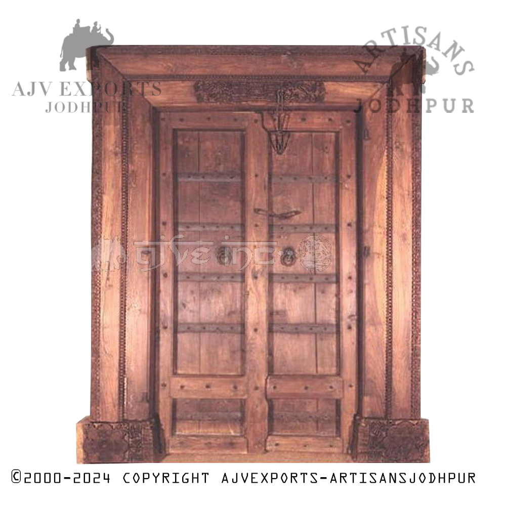 A rustic antique door with brass plates and traditional Indian carvings.