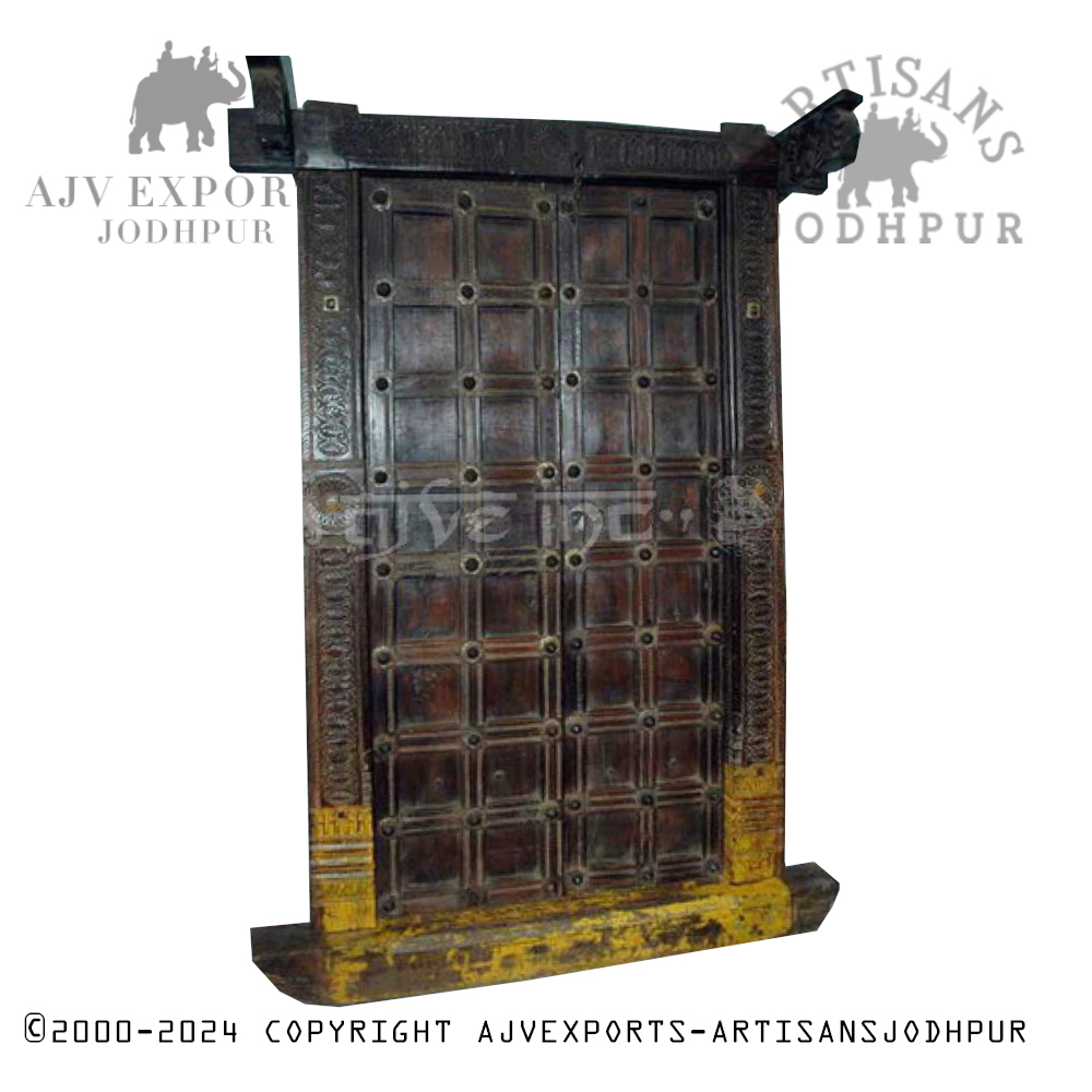 Vintage wooden door with iron studs and a carved frame, reflecting traditional Jodhpur design.