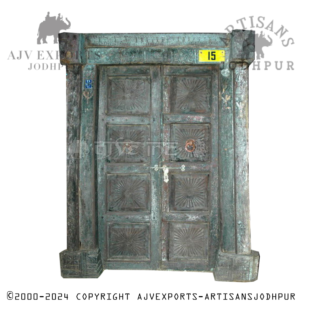 An aged teal wooden door adorned with traditional carvings and a distressed finish, blending cultural heritage with timeless beauty.