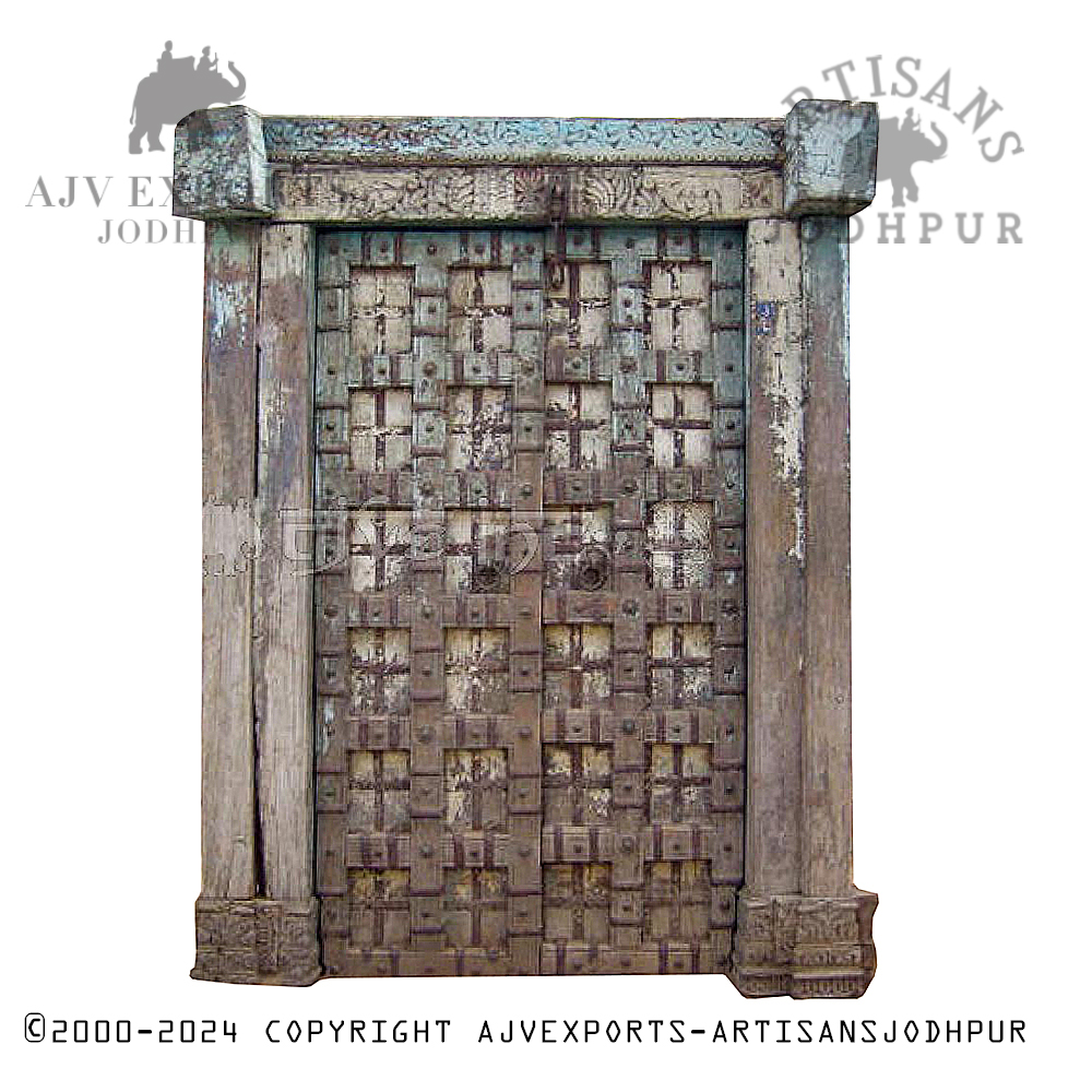 Large antique wooden door with intricate carvings and weathered two-tone finish