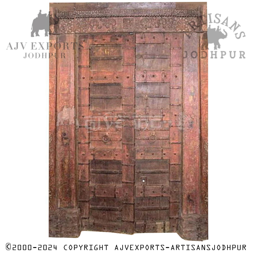 Weathered wooden door with intricate carvings, metal studs, and reddish-brown patina