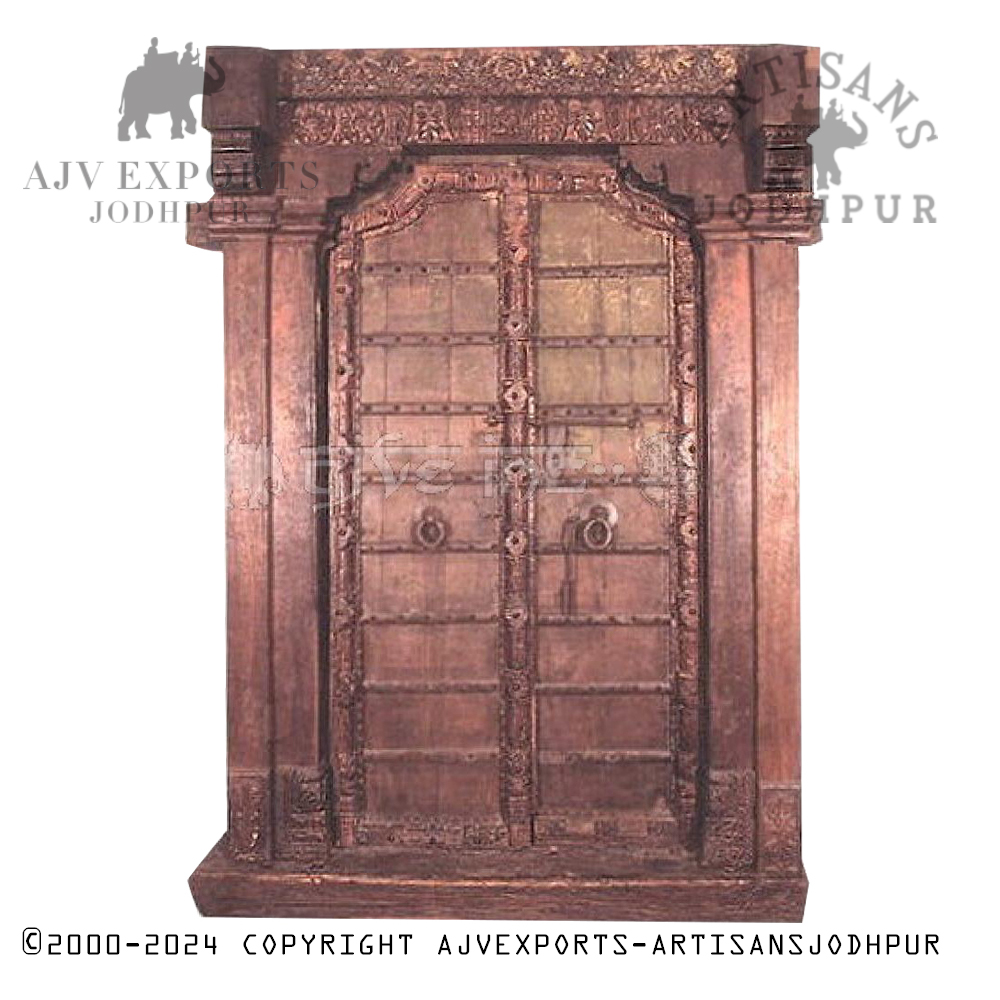 Antique Indian wooden door with floral carvings and metal straps.