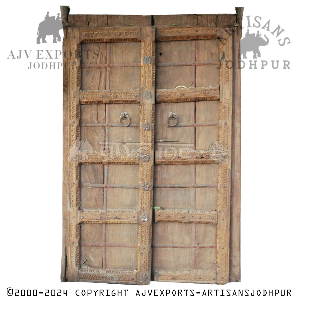 A weathered Indian wooden door with traditional carved accents and rustic metal fixtures.