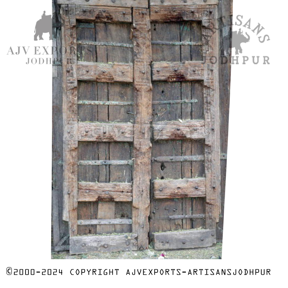 Aged Indian wooden door reinforced with iron bars, showing signs of weathering and a rustic charm.