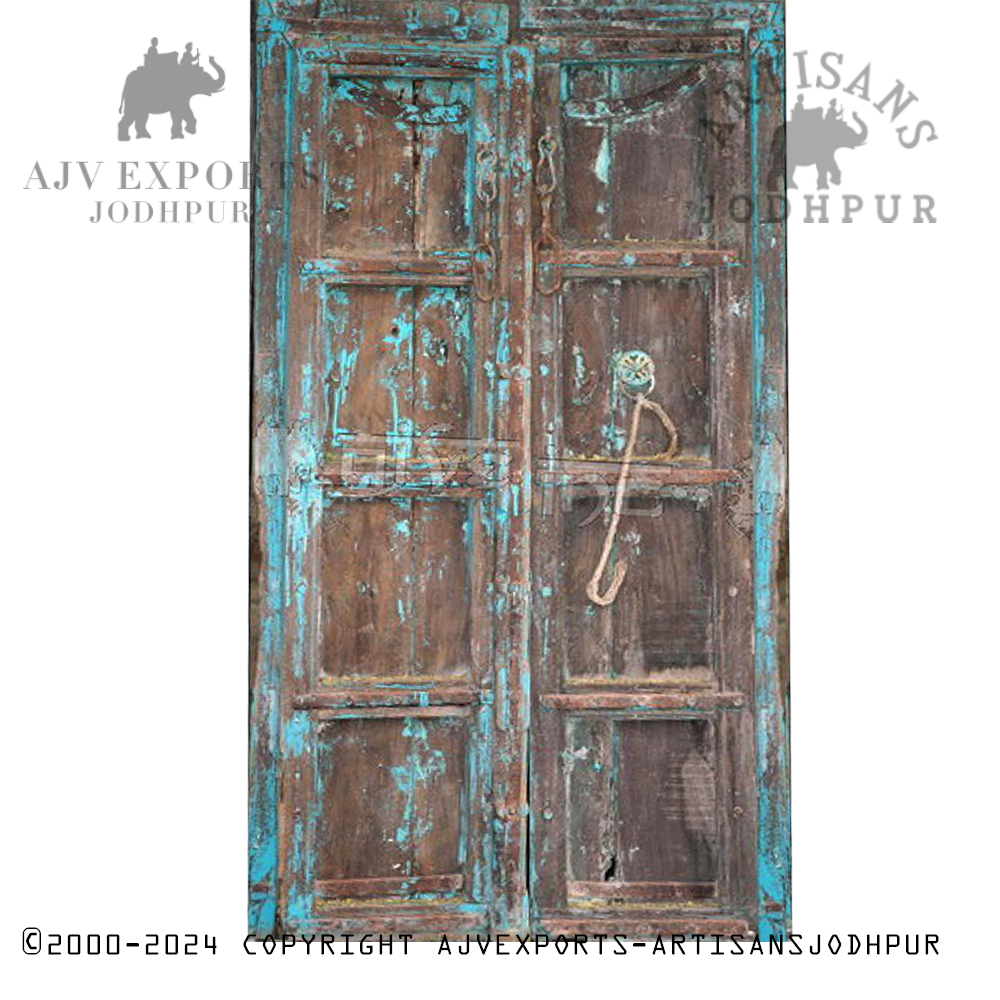 Antique Indian door with faded turquoise paint and traditional design elements.