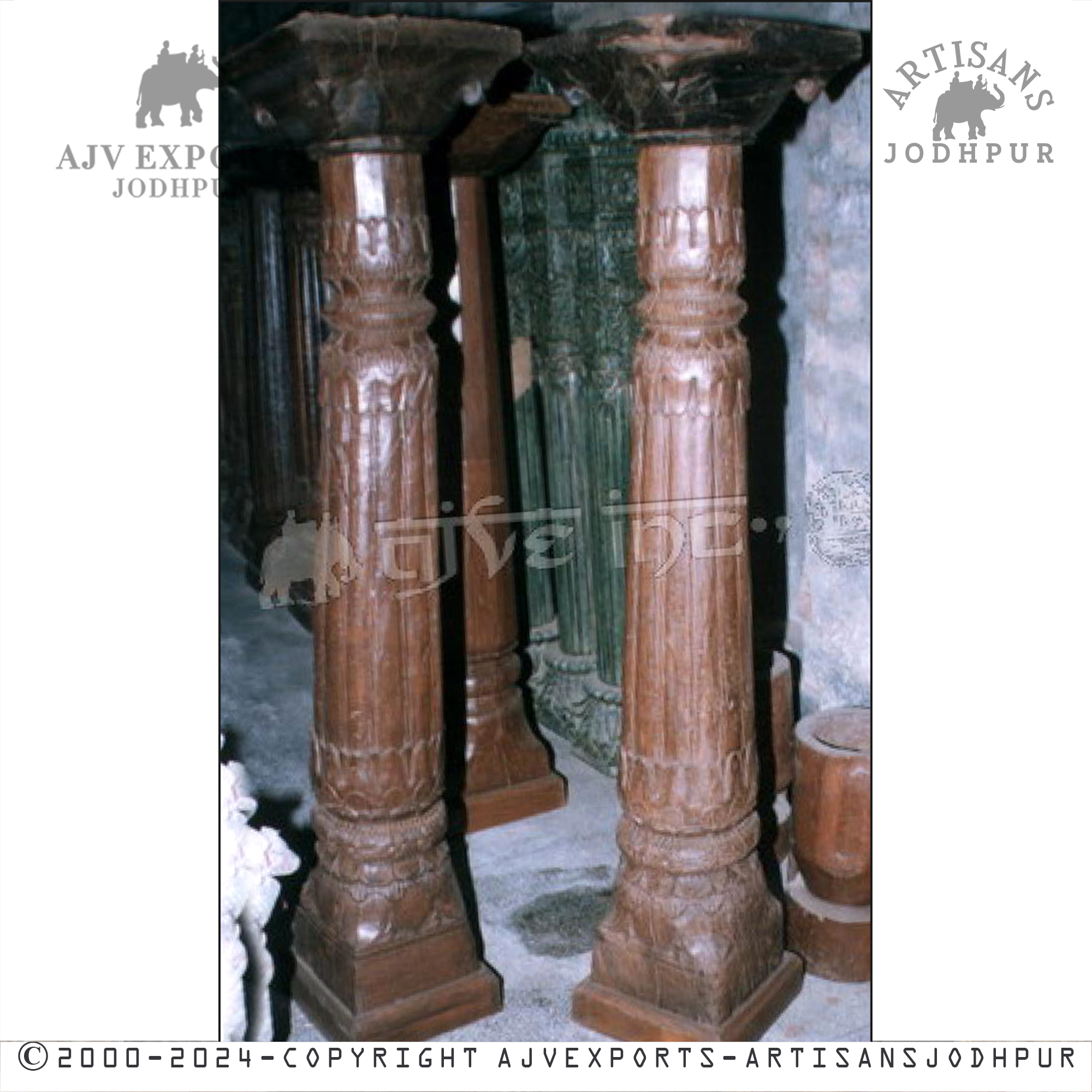 Two classic brown wooden columns with detailed fluting, displayed in a dark, antique setting.