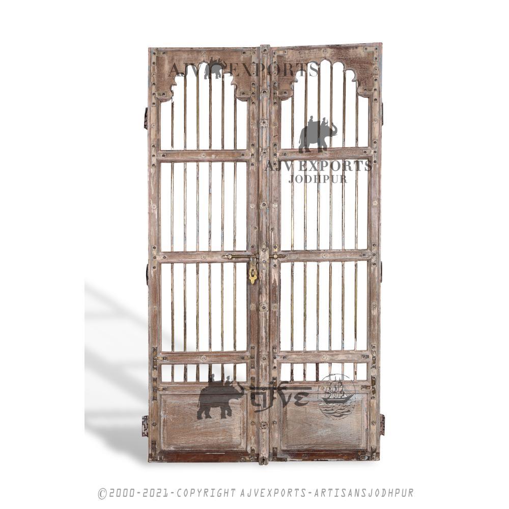 Weathered wooden door with vertical iron bars and intricate metalwork