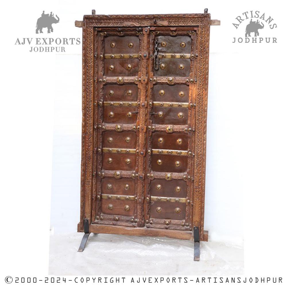 Antique wooden door with brass embellishments and intricate carvings.